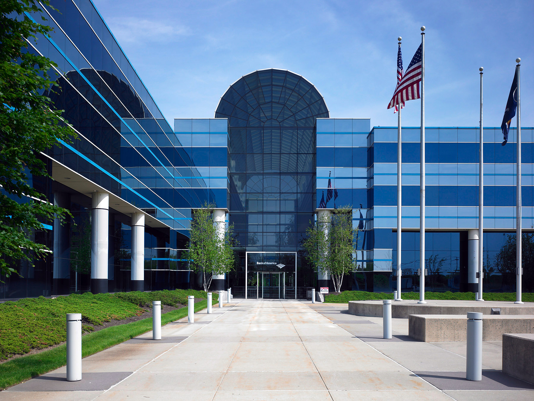 Large office building with sidewalk leading to front door. American Flag out front